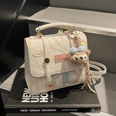Tabletop display of cream patchwork mini backpack with flap, front view.