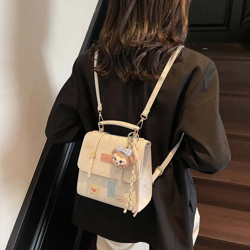 On-model cream patchwork mini backpack with chain straps, three-quarter back view indoors.
