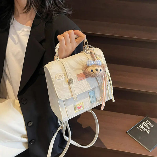 On-model cream patchwork mini backpack with flap and chain straps, handheld at side on stairs.