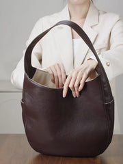 Leather Crescent Hobo Bag shown in brown with a person demonstrating its spacious design, perfect for everyday use.