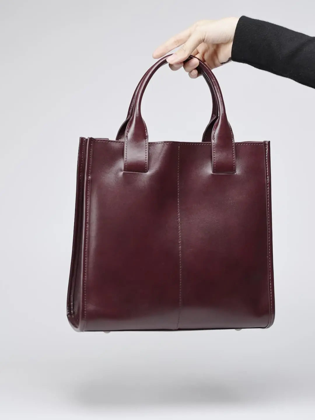 Top-Handle Leather Tote held by hand, lightweight and compact for everyday use, perfect for work or casual outings.