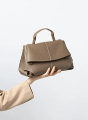 Premium Leather Crossbody Bag in khaki held by a model, showcasing its flap closure and minimalist design.