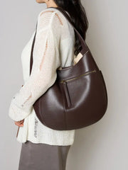 Leather Crescent Hobo Bag shown in rich brown color, styled as a shoulder bag with a sleek design and zip pocket.