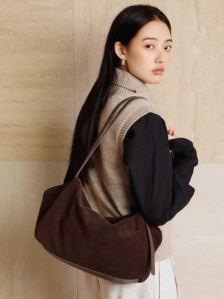 Woman wearing a Suede Leather Pillow Hobo Bag with dual shoulder straps, showcasing a chic and practical style.