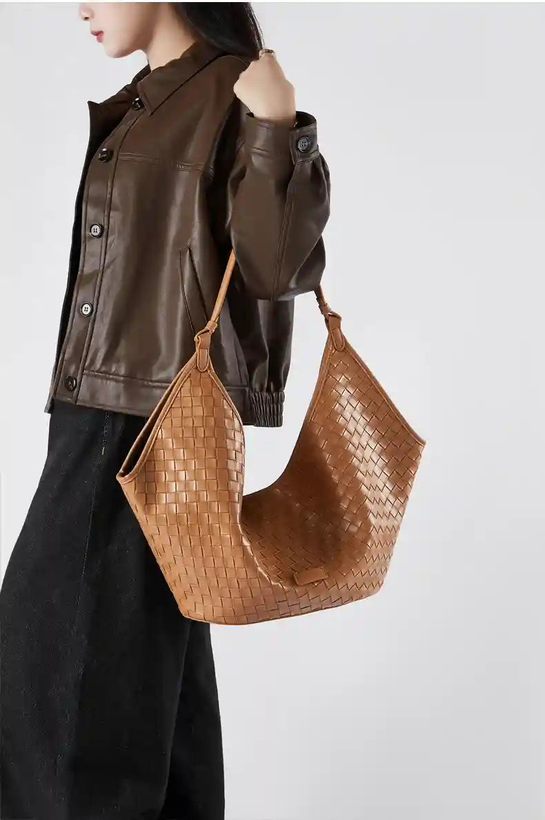 Model showcasing a Large Woven Shoulder Bag in tan color, paired with a brown leather jacket and black pants.