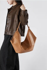 Model showcasing a Large Woven Shoulder Bag in tan color, paired with a brown leather jacket and black pants.