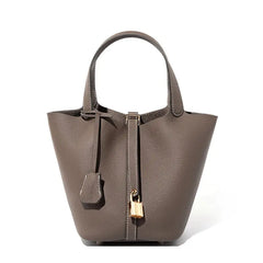 Classic Leather Bucket Bag in neutral tone with minimalist design, showcasing top-handle and drawstring features.