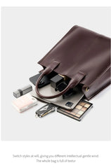 Top-Handle Leather Tote with accessories like laptop, makeup, and wallet on a clean surface.