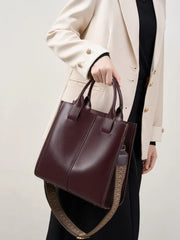 Top-Handle Leather Tote in burgundy carried by a woman wearing a blazer, showcasing its elegant design and versatile straps.