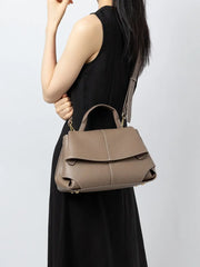 Premium Leather Crossbody Bag in khaki color held by a model wearing a black dress, showcasing its urban minimalist design.