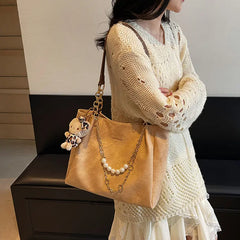 On-model tan canvas shoulder tote with pearl chain, shoulder carry, side view.
