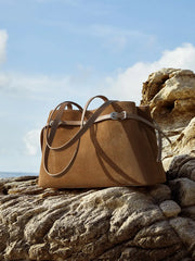 Suede Leather Baguette Shoulder Bag in brown on rocky terrain with adjustable strap for versatile styling.