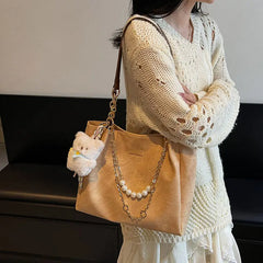 On-model tan canvas shoulder tote with pearl chain, front view at waist.