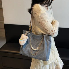 On-model gray canvas shoulder tote with pearl chain, partial body view.