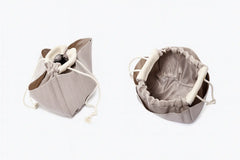 Classic Leather Bucket Bag in neutral tone, featuring top-handle and drawstring design, showcasing minimalist style.