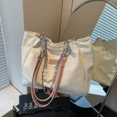 Tabletop display of cream canvas shoulder tote with beaded handles, front view.