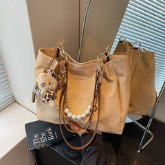 On-model tan canvas shoulder tote with pearl chain, strap on shoulder, near window.